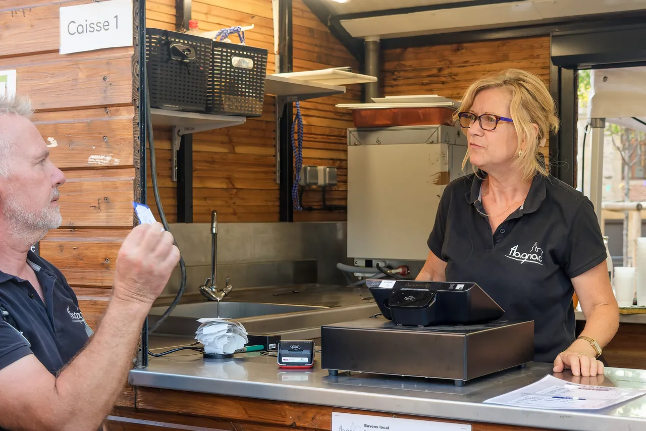 Stand de restauration lors d'un événement en plein air : le vendeur encaisse une cliente sur une tablette de caisse enregistreuse shopcaisse.