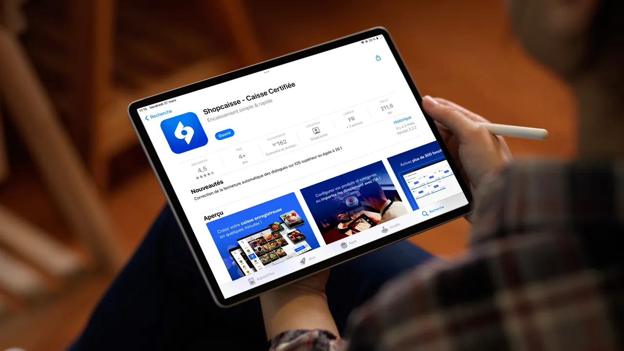 Main tenant un iPhone montrant la page App Store de l'application shopcaisse