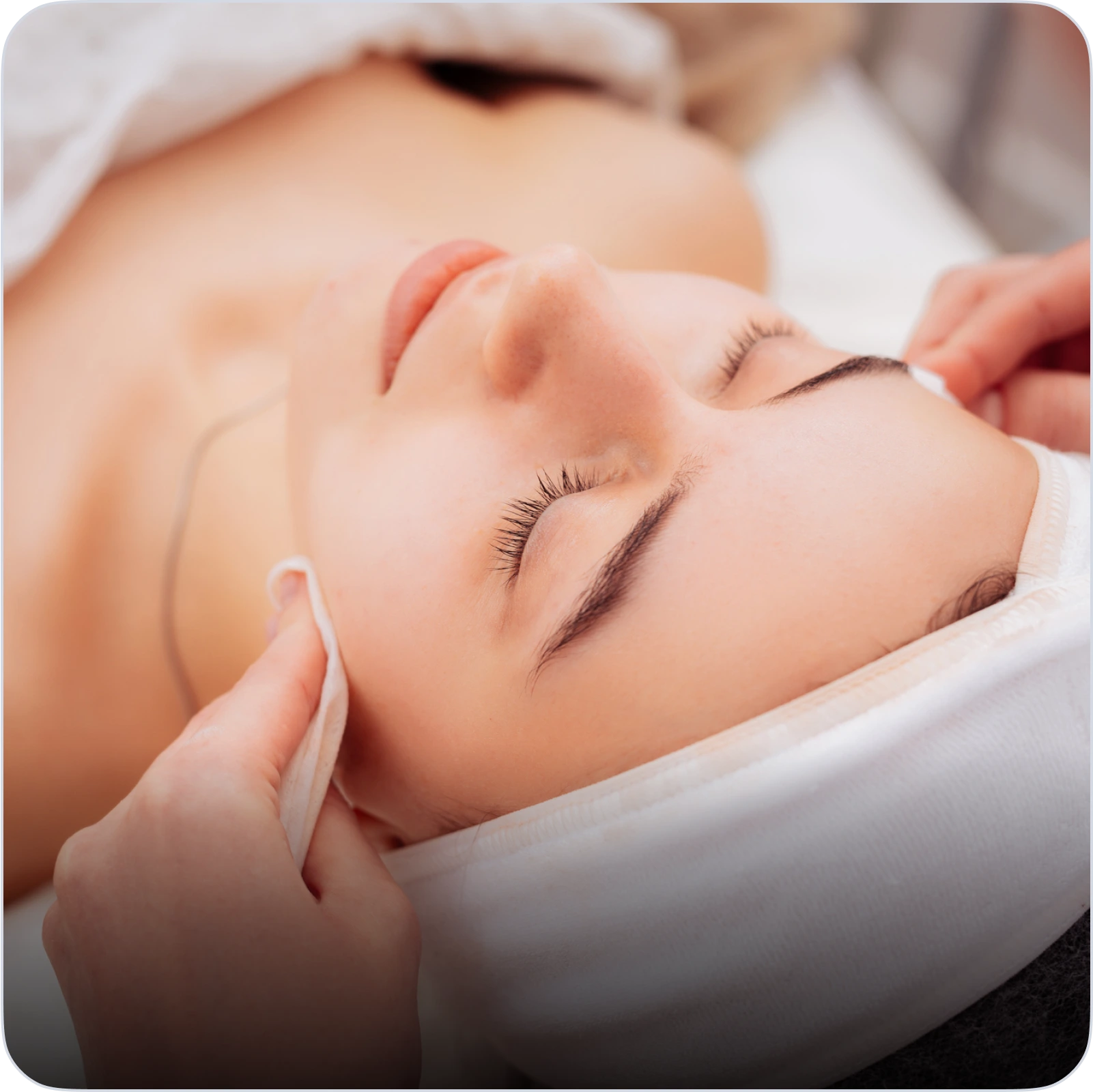 Femme recevant un massage facial relaxant dans un spa ou institut de beauté.