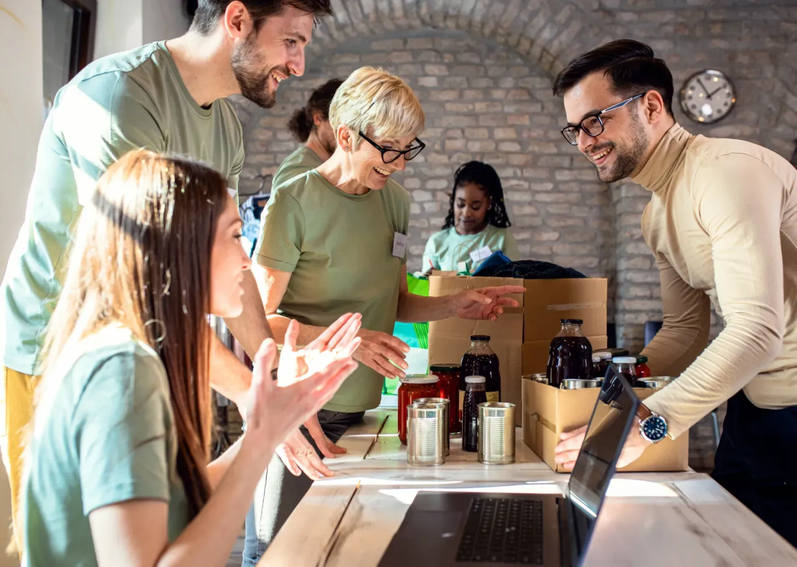Groupe de bénévoles en t-shirts verts triant des donations dans des cartons lors d'une collecte.