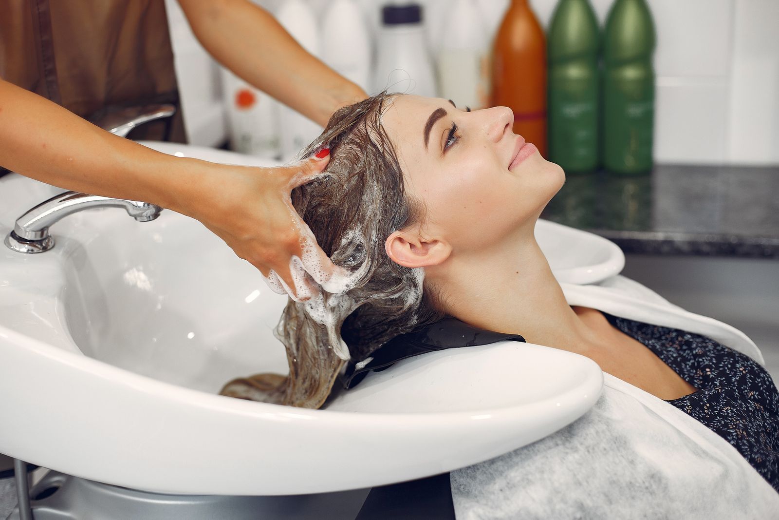 Une femme se fait laver les cheveux par une coiffeuse dans un salon de beauté.