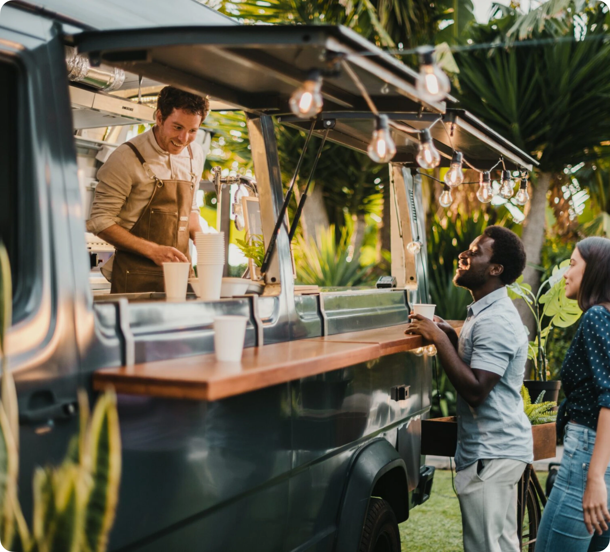 Food truck stationné en festival avec menu sur ardoise et équipe servant des clients en file.