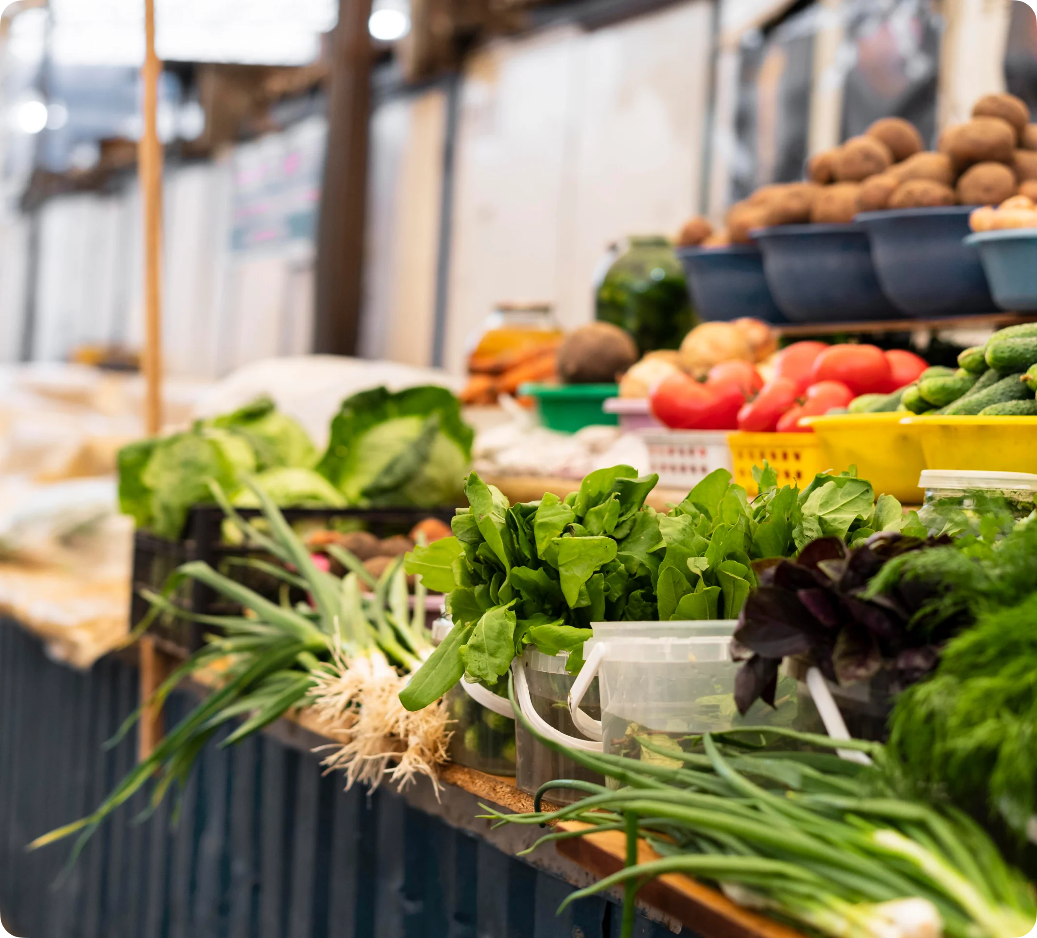 Étal de marché en plein air avec produits frais en présentation et commerçant servant une cliente.