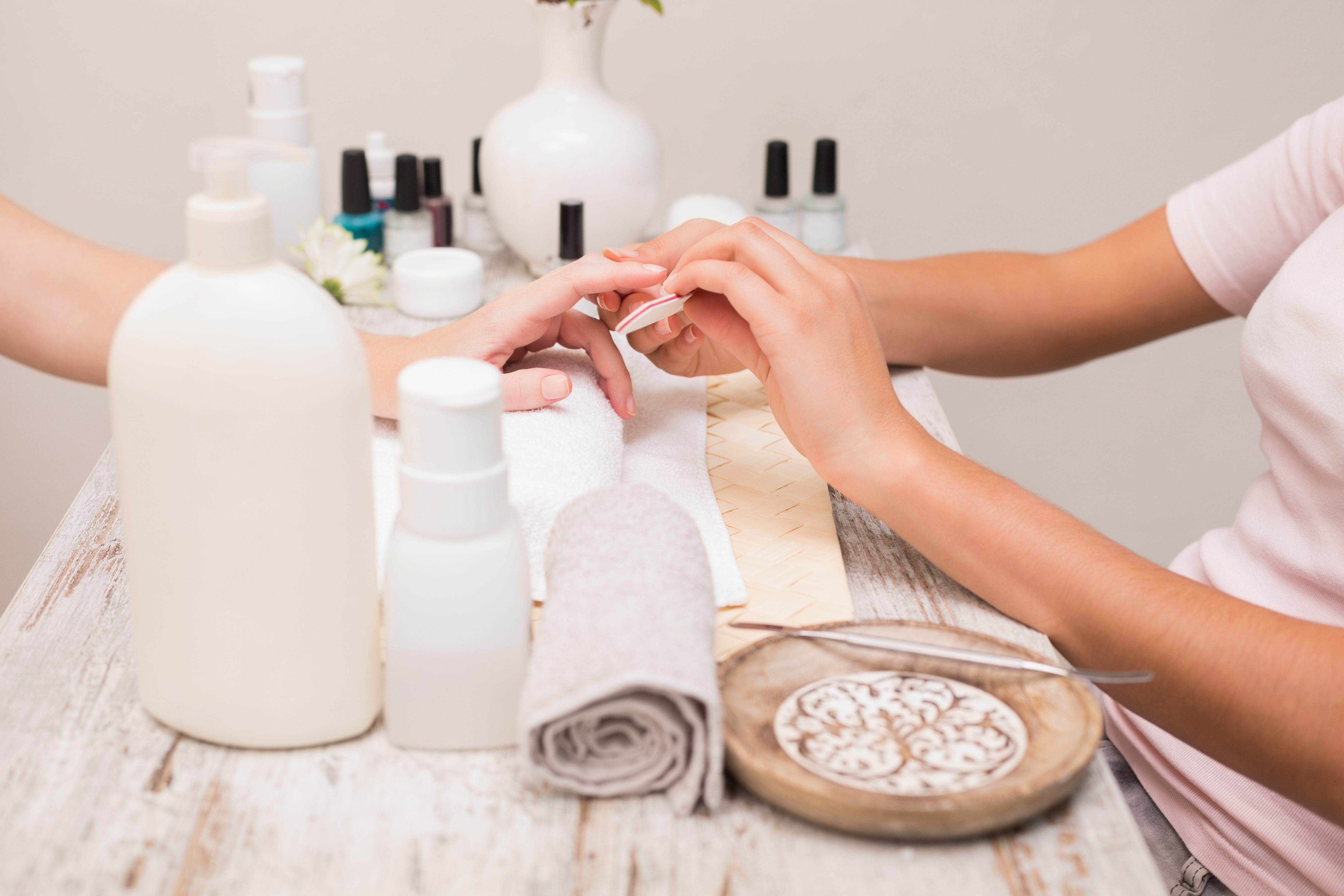 Mains appliquant vernis à ongles lors d'une séance de manucure en salon de beauté.