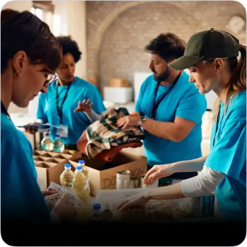 Groupe de bénévoles en gilets bleus triant des fournitures alimentaires et articles de donation.