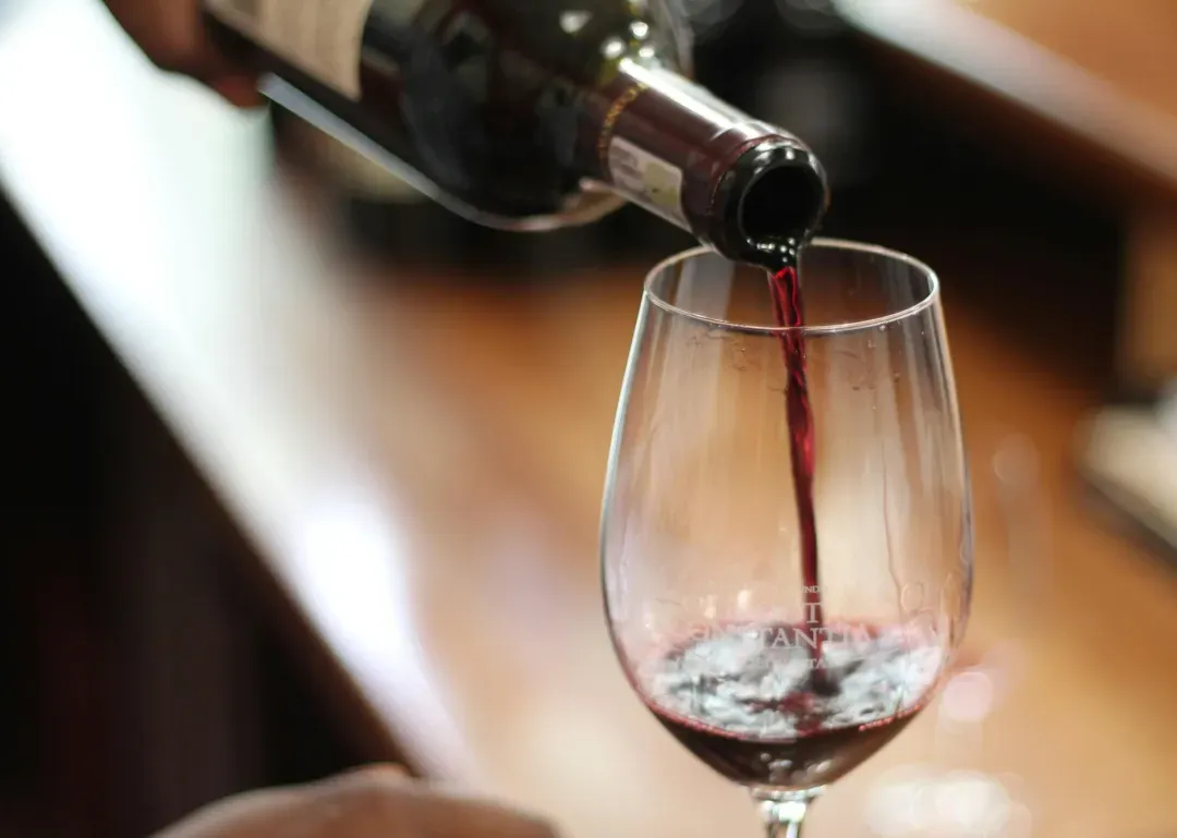 Du vin rouge versé d'une bouteille dans un verre transparent lors d'une dégustation.