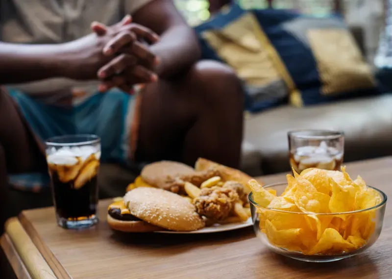 Table avec snacks, boissons et personnes se tenant la main lors d'un repas partagé.