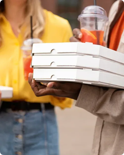 Personne tenant des boîtes à pizza blanches lors d'une livraison de commande.